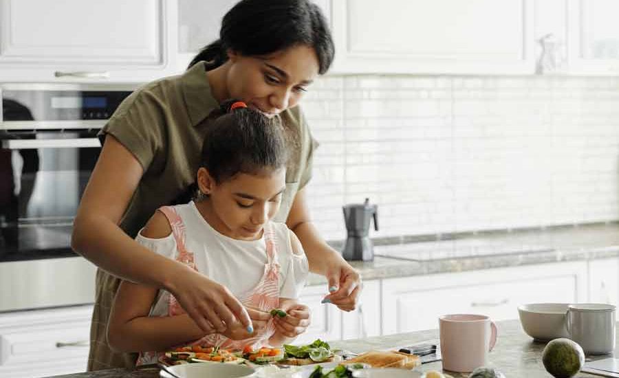 Perempuan bisa Memasak, Masih Penting ya? Seorang ibu mengajar anak perempuannya memasak di dapur (foto: August de Richelieu | pexels)